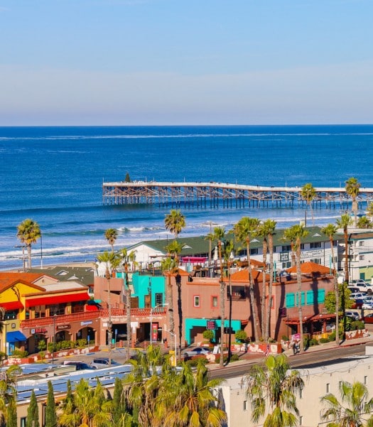 Scenic view of Pacific Beach, showcasing vibrant buildings and a picturesque pier, ideal for highlighting the benefits of converting a garage to living space in this beautiful coastal area.