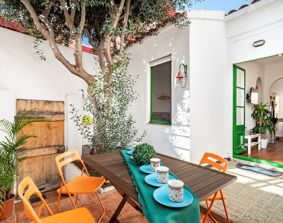 Spanish style ADU patio with vibrant colors, outdoor dining area, and lush greenery.